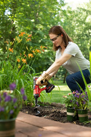 Photo of a person using a CRAFTSMAN CMCA320C1 cordless drill in a garden, with flowers and soil visible.