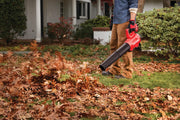 Photo of Craftsman leaf blower SKU CMCBL720M1 in use, blowing leaves on a lawn near a house.