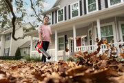 Photo of a person using a CRAFTSMAN cordless leaf blower, SKU CMCBL730P1, on a driveway next to a house.