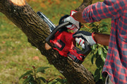 Photo of a CRAFTSMAN 20V cordless chainsaw, SKU CMCCS620B, cutting a tree branch outdoors with a person wearing gloves.