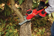 Photo of CRAFTSMAN chainsaw CMCCSL621B trimming tree branch outdoors, red tool held by gloved hands.