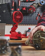 Photo of Craftsman CMCE010B red cordless jobsite fan on a workbench with tools and hardware in the background.