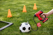 Photo of CRAFTSMAN CMCE521B inflator used to inflate a soccer ball on grass, cones and goal net visible in background.