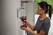 Person using red Craftsman cordless impact driver CMCF610B to install metal wall shelf bracket indoors.