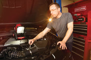 Photo of CRAFTSMAN CMCL030B work light illuminating car engine in garage with CRAFTSMAN tool chest in background.