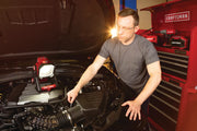 Photo of CRAFTSMAN CMCL030B work light illuminating a car engine bay, person working, red tool chest in background.