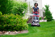 Photo of a person mowing a lawn with a Craftsman self-propelled lawn mower, SKU CMCMWSP320X2, near a house.