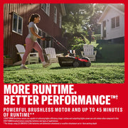 Photo of a Craftsman lawn mower CMCOE210P2 in use on a grassy yard, woman pushing mower near red house.