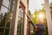 Photo of Craftsman CMCPS520D1 power scrubber cleaning an exterior house window, held by a person outdoors.