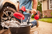 Photo of Craftsman power scrubber CMCPSMB with red brush head splashing water while being used outdoors near a bucket.