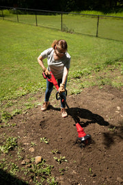 Person using CRAFTSMAN cultivator CMCTL320B in a garden, tilling soil on a sunny day.
