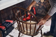 Photo of Craftsman CMCW221B cordless detail sander in use on a wooden chair, toolbox visible in background.