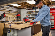 Photo of person using CRAFTSMAN CMCW350B belt sander on wooden board in workshop, workbench and tools visible.