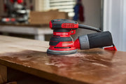 CRAFTSMAN random orbital sander on a wooden surface, featuring a dust collection bag in a workshop setting.