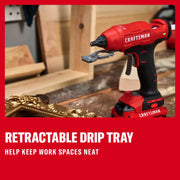 Photo of Craftsman hot glue gun with retractable drip tray, SKU CMGL200B, on a workshop table with wood and gold frame.