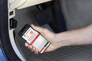 Photo of a hand holding a phone using the CRAFTSMAN CMMT77695 diagnostic tool under a car dashboard near pedals.