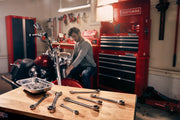 Photo of CRAFTSMAN ratcheting wrenches set SKU CMMT87023 on workbench, motorcycle and red tool storage in background.