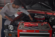 A person working on a car engine, with a red CRAFTSMAN tool chest in the foreground displaying various tools and socket sets.