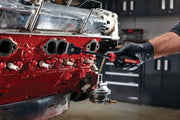 Photo of a hand using a CRAFTSMAN screwdriver, SKU CMMT98329, to work on a red engine block in a workshop.