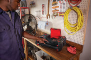 Photo of CRAFTSMAN portable radio CMST17510 on a workbench with a person adjusting the controls in a garage.