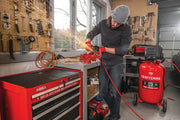Photo of a Craftsman air compressor, SKU CMXECXM331, in a workshop next to red tool chest, shown in use with power tool.