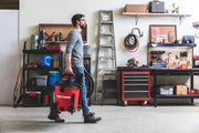 Photo of person carrying a red Craftsman wet/dry vacuum, SKU CMXEVBE17590, in a garage workshop setting.