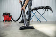 Photo of a person cleaning a concrete floor with a Craftsman wet/dry vacuum, SKU CMXEVBE17607, wide nozzle attachment.
