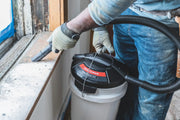 Photo of Craftsman wet/dry vac CMXEVBE17678 in use, cleaning debris from a window sill, partial view of user in gloves.