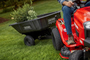 Photo of a Craftsman tow-behind cart, SKU CMXGRAM201302, attached to a red lawn tractor, filled with green plants.