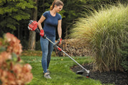 Photo of person using Craftsman string trimmer CMXGTAMDSS25 in a garden, cutting grass near ornamental plants.