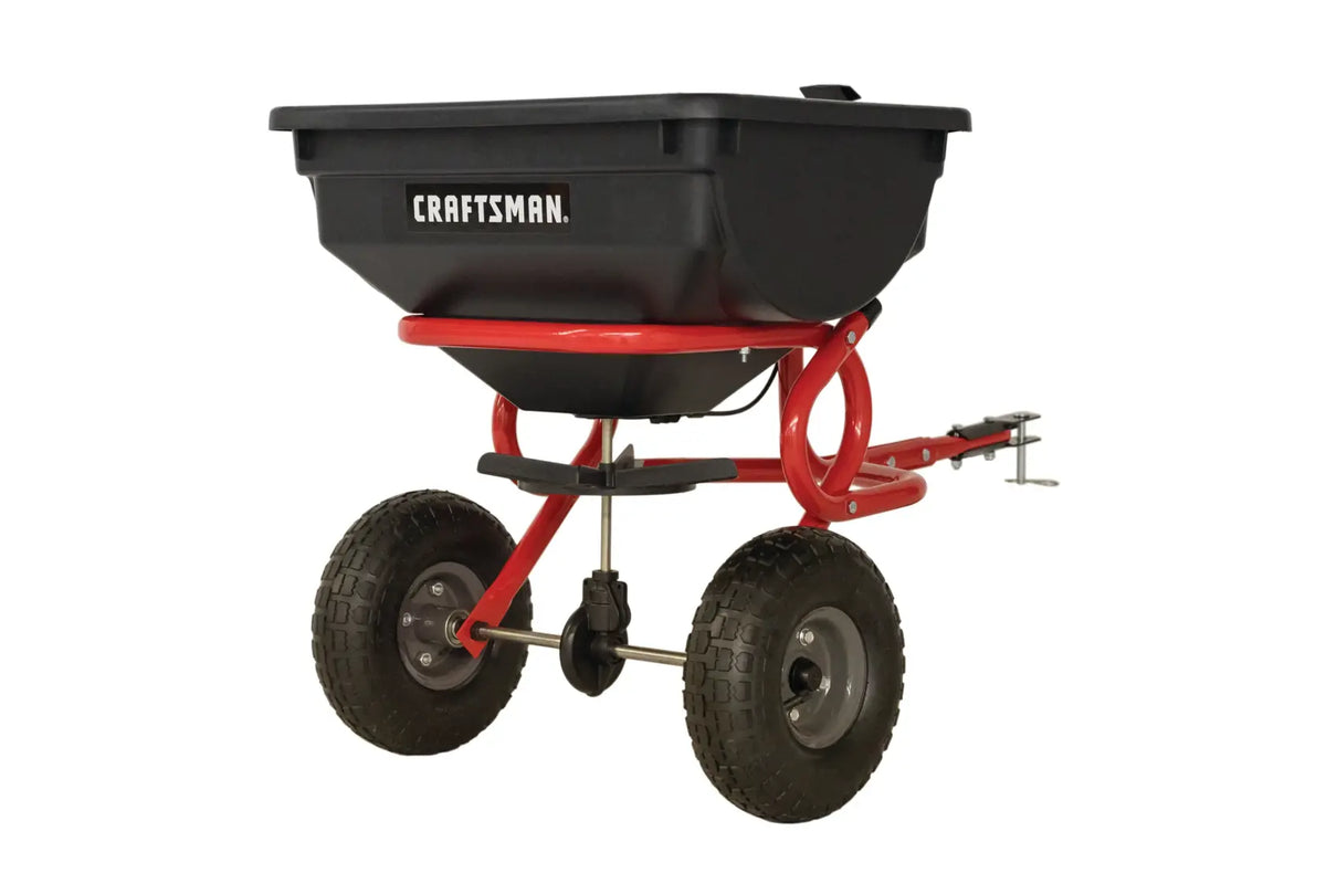 Photo of Craftsman tow-behind spreader, SKU CMXGZBF7124322, black and red, product angle on white background.
