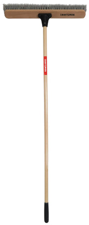 Photo of Craftsman push broom CMXMLBA8224A with wooden handle, wide brush head, and gray bristles, front angle.