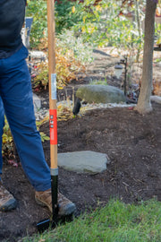 Photo of CRAFTSMAN CMXMLTP35324 edging tool with wooden handle in use on garden soil, user standing beside tool.