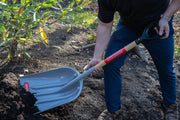 Photo of person using a CRAFTSMAN scoop shovel, SKU CMXMLTP35332, gray blade with wood handle, for outdoor gardening.