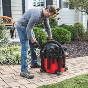 Person using Craftsman wet/dry vacuum CMXZVBE38660 on a patio near garden, visible hose and attachments.
