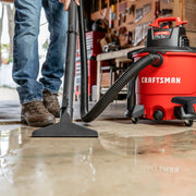 Photo of Craftsman wet/dry vacuum CMXZVBE38675 cleaning water from garage floor, close-up of vacuum and hose.