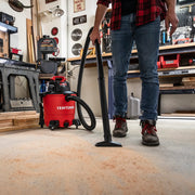 Photo of a person using a Craftsman wet/dry vacuum CMXZVBE38675 to clean sawdust on a workshop floor.