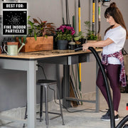 Craftsman vacuum hose CMXZVBE38735 cleaning soil on workbench with plants and gardening tools indoors.