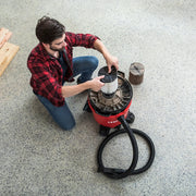 Photo of person installing a filter in a red Craftsman wet/dry vacuum, SKU CMXZVBE38755, top view in workshop.