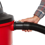 Photo of a hand attaching the black hose to a red CRAFTSMAN wet/dry vacuum, SKU CMXZVBE38763, close-up angle.