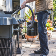 Photo of person using CRAFTSMAN ash vacuum SKU CMXZVBE43268 to clean a grill outdoors, showing vacuum and grill details.
